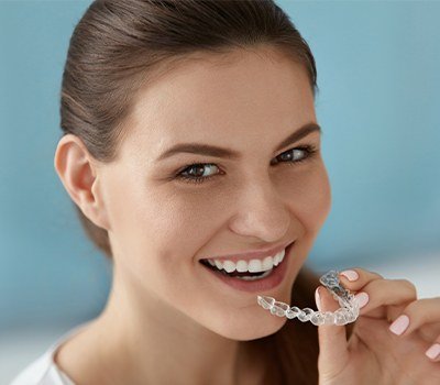 woman holding Invisalign clear braces tray