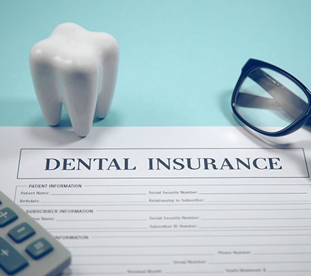 Dental insurance form, eyeglasses, and calculator on blue background
