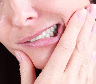 woman holding jaw in need of wisdom tooth extraction