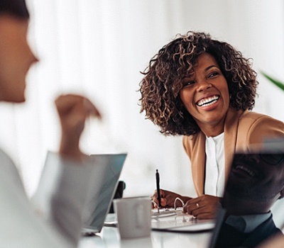 someone smiling and sitting with a coworker at a desk