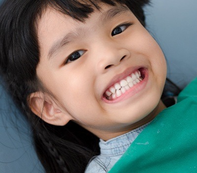 little girl smiling big after tooth-colored filling placement
