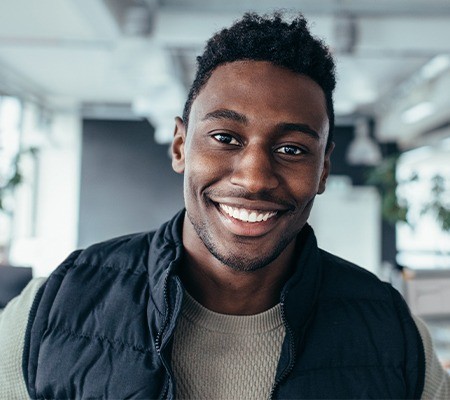 man in vest smiling after cosmetic dentistry