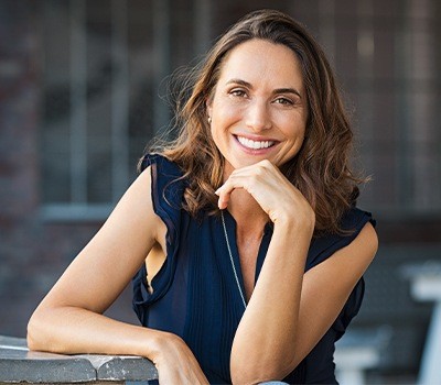 woman in blue dress smiling after dental crown restoration