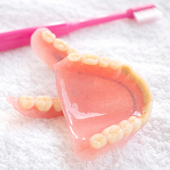 Set of dentures next to a toothbrush