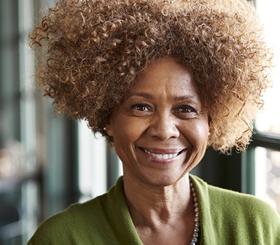 a person smiling and sitting down in front of a window