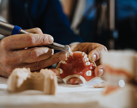Lab worker carefully painting a set of dentures