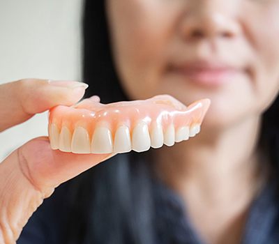 Woman holding dentures