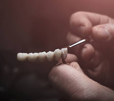 Lab technician painting replacement teeth