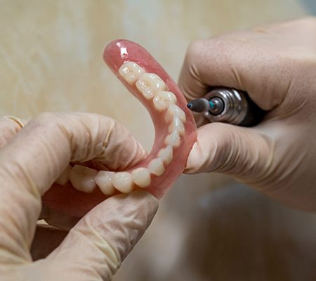 Lab technician filing dentures