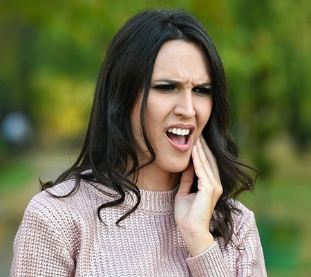 woman with in need of emergency dentistry holding cheek