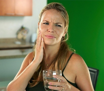 woman holding cheek in need of emergency dental care