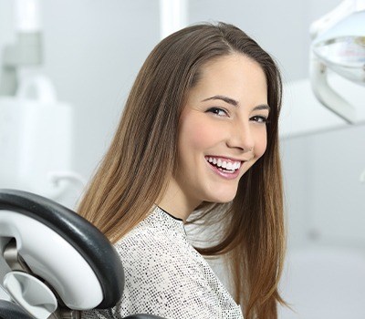 woman smiling over shoulder after emergency dentistry
