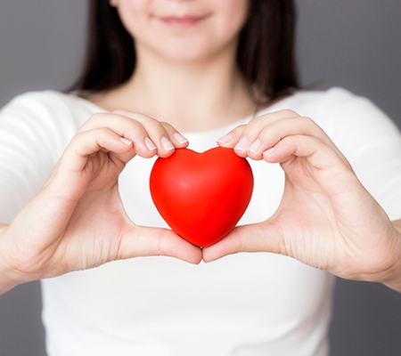 person holding a red love heart in front of their chest 