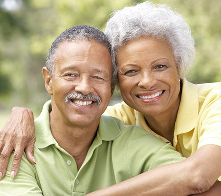 Older couple with dental implants in Bowie smiling and hugging.