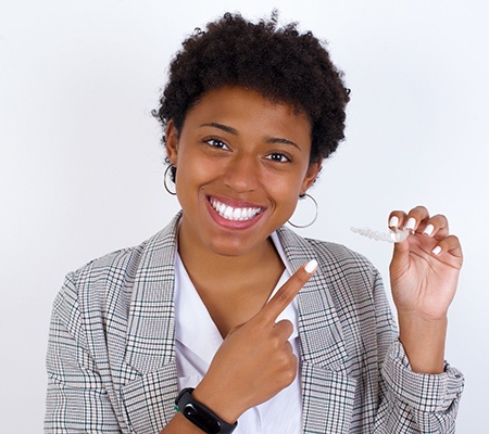 Woman smiling and pointing at Invisalign in Bowie
