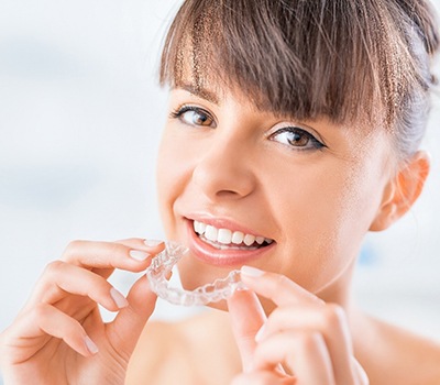 A woman preparing to insert an Invisalign aligner into her mouth