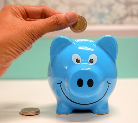 Hand putting coin in blue piggy bank