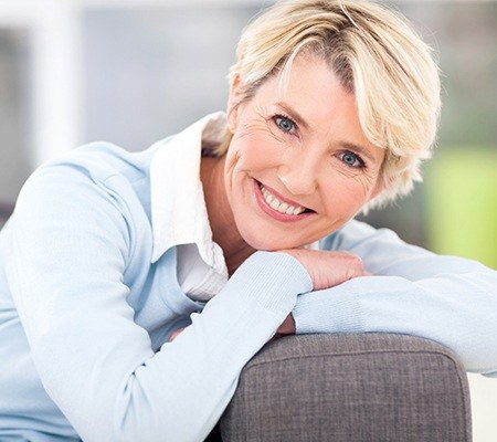 woman in blue smiling after tooth replacement