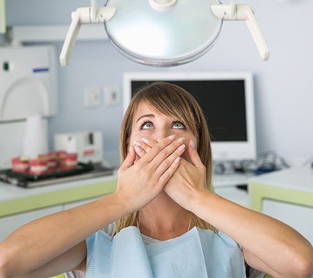 Fearful woman in need of sedation covering smile