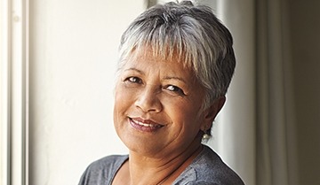 woman in grey smiling after replacing missing teeth