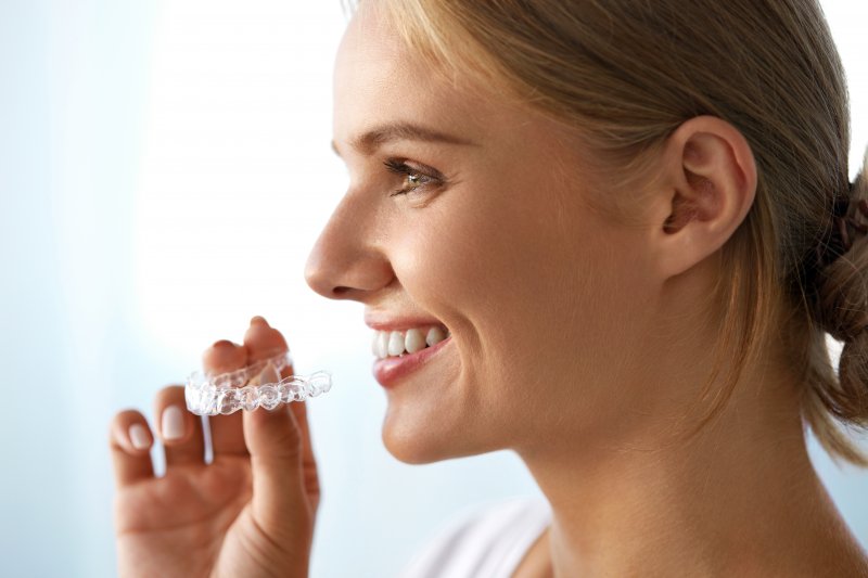 woman holding Invisalign tray and smiling