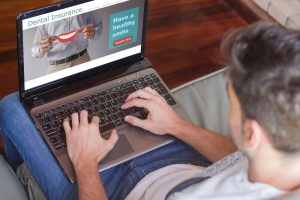 Man using laptop to find information about dental insurance