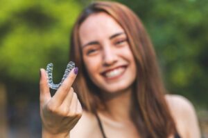 Woman holding clear aligner. 