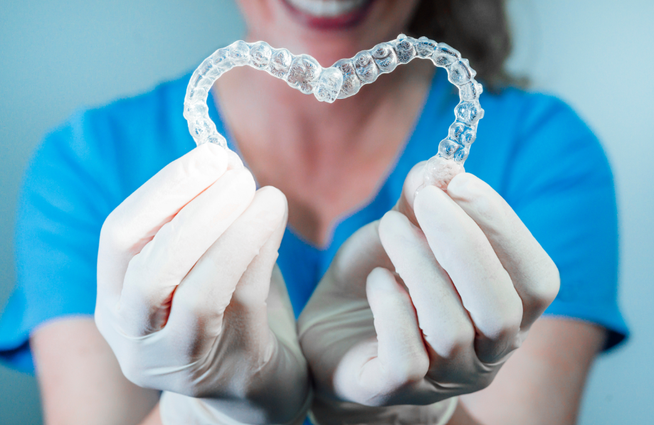 Dentist holding clear aligners in a heart shape